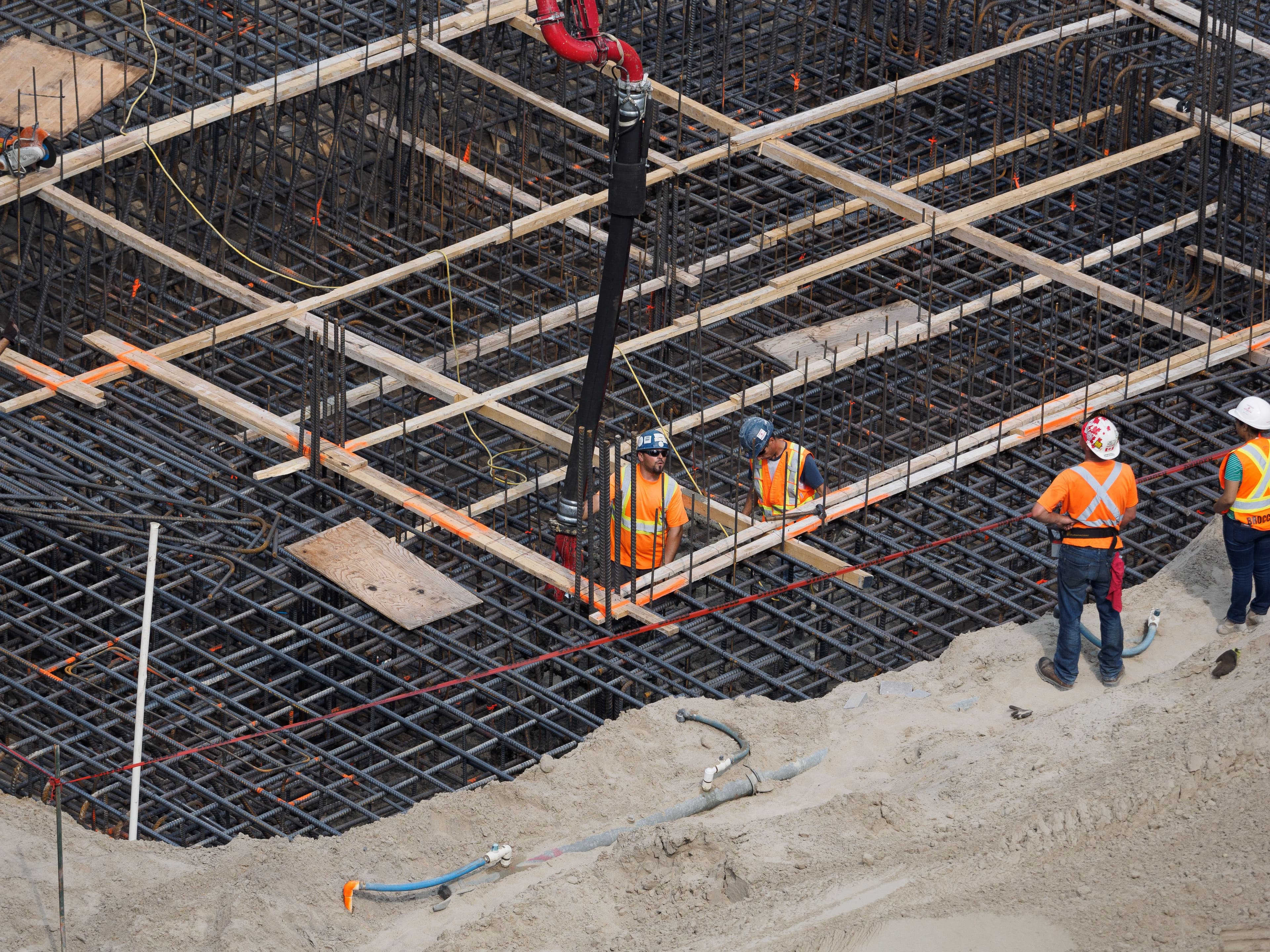 Construction workers reinforcing a steel foundation at a building site
