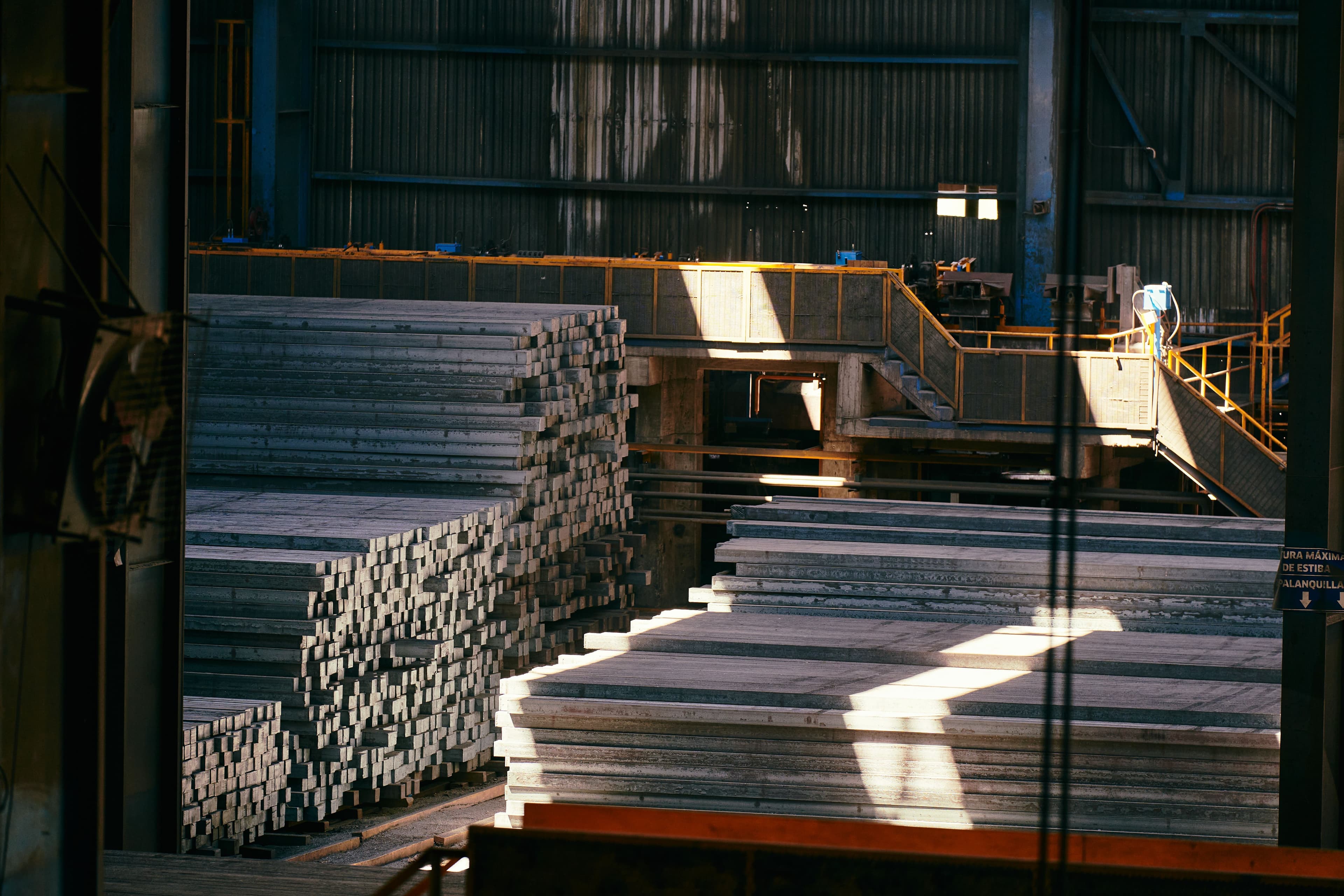 Stacked structural steel billets in an industrial warehouse